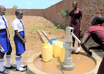 students pumping water from borehole